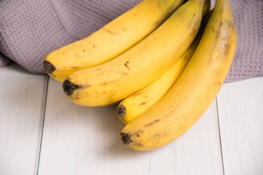 Bozuk kabuklu bir muz dalı ve gri ışık masasında bir mutfak havlusu..