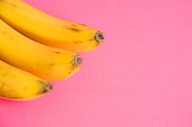 Pembe arka planda çürük derili bir muz dalı.