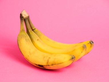 Pembe arka planda çürük derili bir muz dalı.