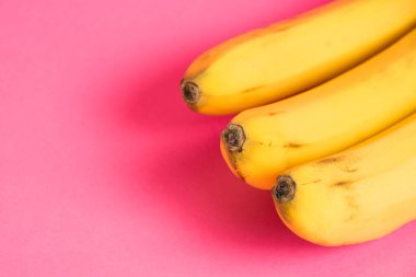 Pembe arka planda çürük derili bir muz dalı.