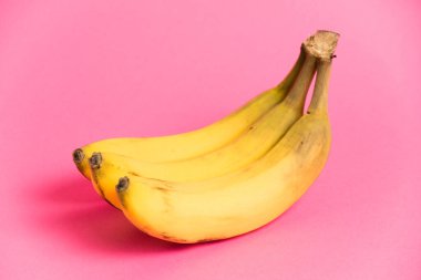 Pembe arka planda çürük derili bir muz dalı.