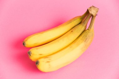 Pembe arka planda çürük derili bir muz dalı.