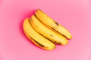 Pembe arka planda çürük derili bir muz dalı.