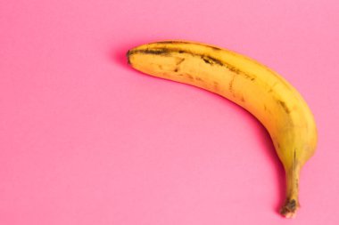 Pembe arka planda şımarık derili muz. Yalnız muzu kurtar..