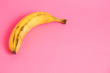 Pembe arka planda şımarık derili muz. Yalnız muzu kurtar..