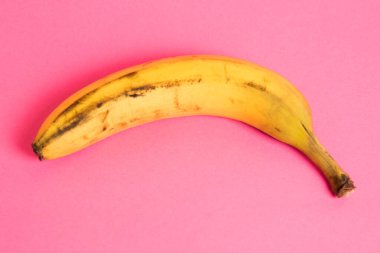 Pembe arka planda şımarık derili muz. Yalnız muzu kurtar..