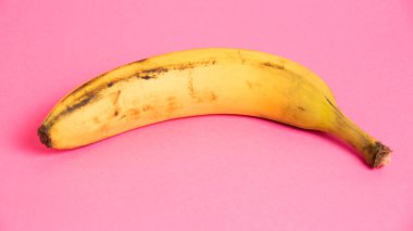 Pembe arka planda şımarık derili muz. Yalnız muzu kurtar..