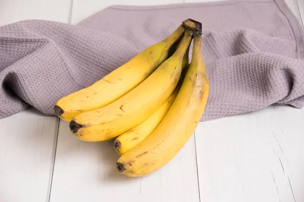 Bozuk kabuklu bir muz dalı ve gri ışık masasında bir mutfak havlusu..