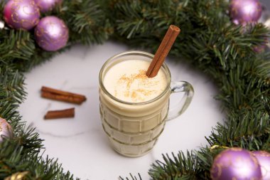Noel resifinin içinde tarçın çubuğu olan bir bardak eggnog fotoğrafının yakın plan konsepti..