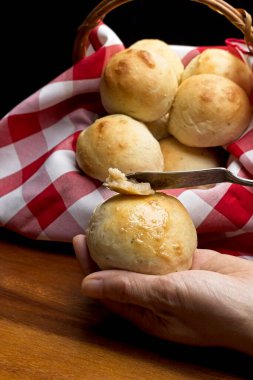 Bir rulo tutan ve rulonun üstüne tereyağı döken ellerin yakın çekimi..