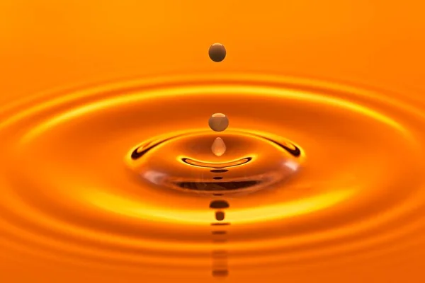 一个抽象的摄影棚照片 照片上的水滴被橙色摄影棚的闪光灯反射到静水中 — 图库照片