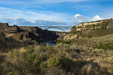 Yılan Nehri 'nin üzerindeki Perrine Köprüsü' nün manzarası ve ön plandaki kuru çalılar Twin Falls, Idaho 'daki alçak güneş tarafından aydınlatılıyor.. 