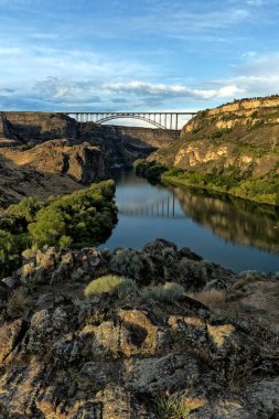 Batan güneşin ışığı, Yılan Nehri boyunca çevreleyen kanyon duvarlarını ve Idaho, Twin Falls 'taki Perine Köprüsünü aydınlatır..