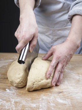 Büyük bir hamur topunu kesmek için hamur kesiciyle kesen bir kadının yakın plan fotoğrafı..