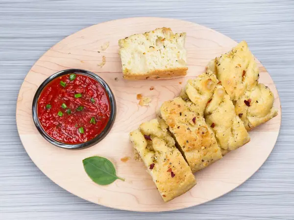 Odaklanmalı ekmek dilimlerinin düz bir fotoğrafı ve daldırmak için bir tabak domates sosu..