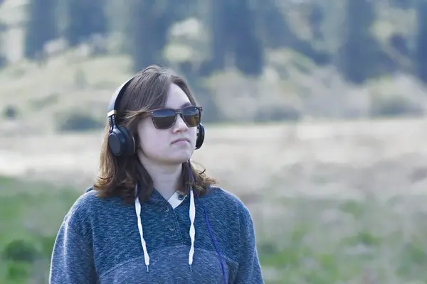 Młoda Kobieta Okularach Przeciwsłonecznych Pogodny Dzień Słucha Muzyki Słuchawkach Podczas Obrazy Stockowe bez tantiem