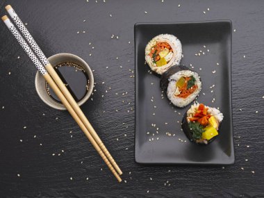 Düz bir stüdyo fotoğrafı dilimlenmiş Kore kimbap tabağı ve soya soslu bir yemek.. 