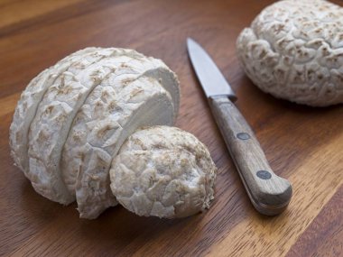 A close up studio photo of a sliced puffball mushroom along with a knife on a cutting board. clipart