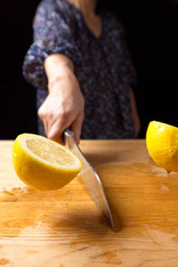 Olgun bir limonu tahta kesme tahtasıyla ikiye bölmenin kavramsal bir fotoğrafı..