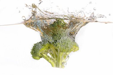 An abstract photo of a head of broccoli being dropped into clear water. clipart