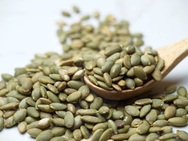 Ahşap bir kaşık ve masanın üzerinde kavrulmuş kabak tohumlarının yakın çekim fotoğrafı..