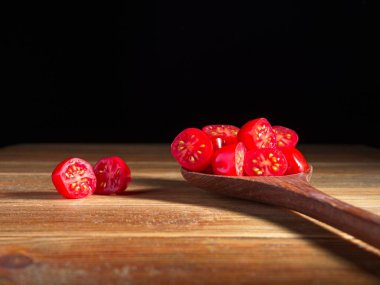 Tahta bir kaşıkta yarım üzüm domatesiyle kesilmiş bir stüdyo fotoğrafı.