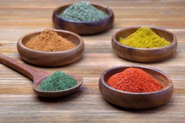 Biber tozu, maydanoz, tarçın ve ahşap kaselerde köri içeren çeşitli baharatlardan oluşan bir stüdyo fotoğrafı..