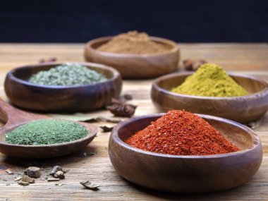 Biber tozu, maydanoz, tarçın ve ahşap kaselerde köri içeren çeşitli baharatlardan oluşan bir stüdyo fotoğrafı..