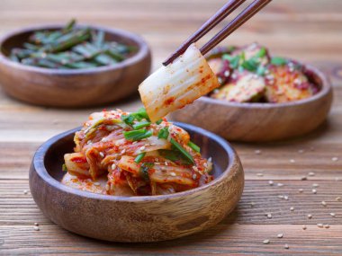 Napa lahana parçalarını ahşap bir kaseden toplamak için çubuk kullanırken çekilmiş yakın çekim bir yemek fotoğrafı..