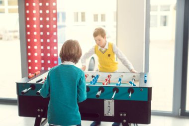 Okuldaki iki öğrenci arasında masa üstü futbolu oynuyorlar.