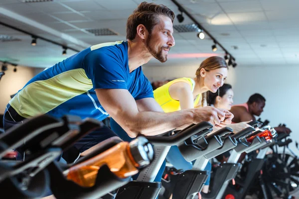 Caucasian man and friends on fitness bike in gym during workout