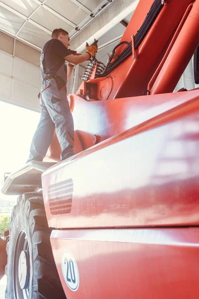 ガレージで巨大な農場機械を修理する優秀な機械工 — ストック写真