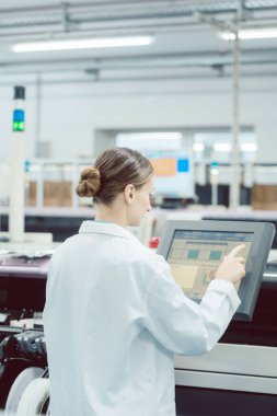 Elektronik fabrikasında üretim hattını kontrol eden kadın.