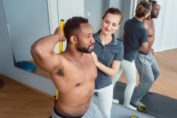 Young black man receiving physical therapy on his shoulder