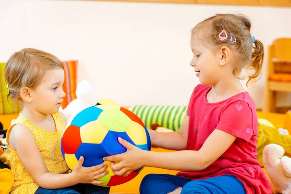 两个女孩在玩学校玩一个五颜六色的球的乐趣 — 图库照片