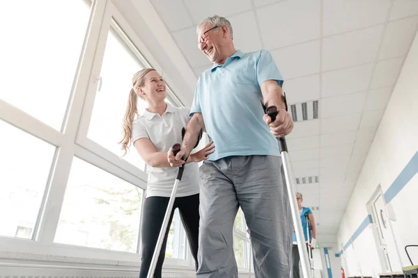 怪我をした後の松葉杖の歩き方を学ぶリハビリテーション科の先輩 — ストック写真