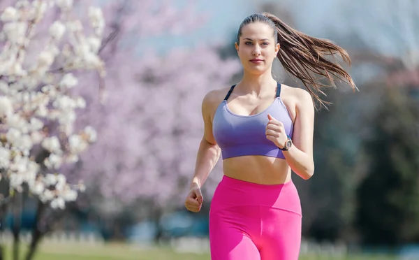 Sportowa Dziewczyna Biegnie Parku Wiosenny Dzień Przed Kwiatem — Zdjęcie stockowe
