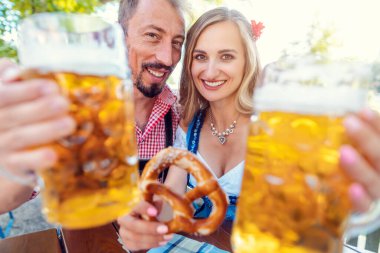 Çift, Bavyera bira bahçesinde kameraya kadeh kaldırıyor