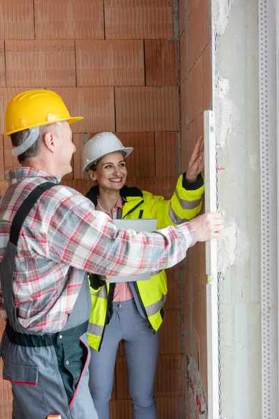 Lächelnde Junge Bauingenieurinnen Weißem Bollenhut Und Arbeiter Gelbem Bollenhut Kontrollieren — Stockfoto