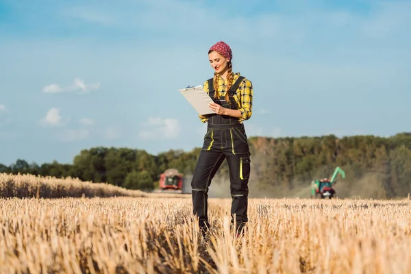 农妇以农业机械为背景监测收获的经营进度 — 图库照片