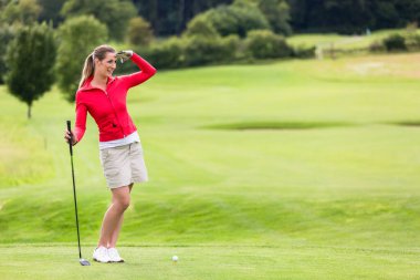 Gülümseyen çekici bayan golfçü sahada dikilirken gözleri koruyor.