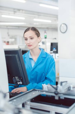 Kadın elektrik mühendisi bir fabrika elektrik üretim hattında çalışıyor..