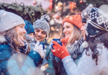 Bir grup arkadaş Noel pazarında soğuktan kavrulmuş şarap içip eğleniyorlar.