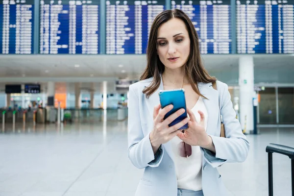 Obchodní Žena Obleku Držící Telefon Stojící Letišti Před Displejem Zobrazujícím Stock Fotografie