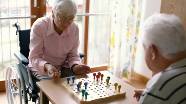 Två Seniorer Man Och Kvinna Ett Vårdhem Spelar Ett Brädspel — Stockvideo