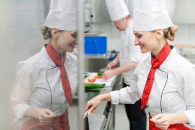 Büyük ticari mutfakta aşçılar birlikte yemek pişirir sosu karıştırırlar.
