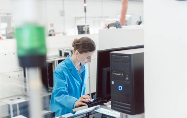 Kadın elektrik mühendisi bir fabrika elektrik üretim hattında çalışıyor..