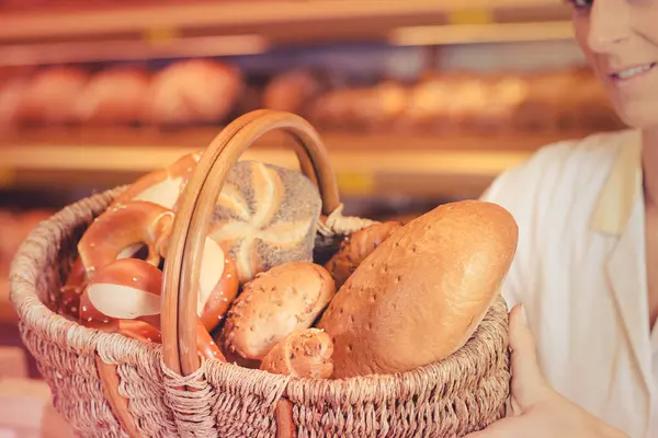 面包店里的女售货员 提着一篮子面包和面包卷 — 图库照片