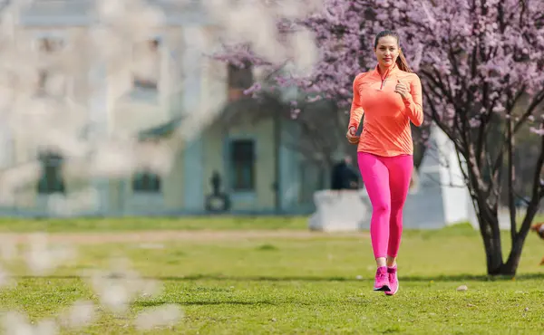 Sportowa Dziewczyna Biegnie Parku Wiosenny Dzień Przed Kwiatem Obrazy Stockowe bez tantiem