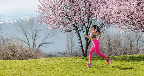 Sportowa Dziewczyna Biegnie Parku Wiosenny Dzień Przed Kwiatem Zdjęcia Stockowe bez tantiem